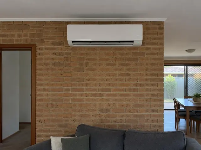 Wall-mounted split system on a brick feature wall in a living room with open louvre in Salisbury North