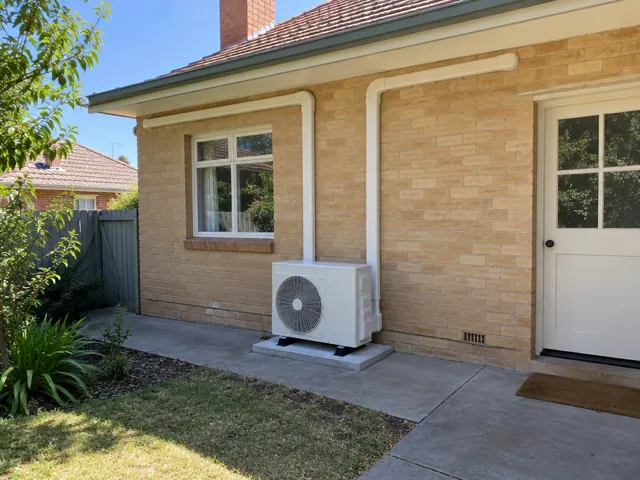 Outdoor AC unit on a concrete pad with neat pipe covers on a brick house in Salisbury